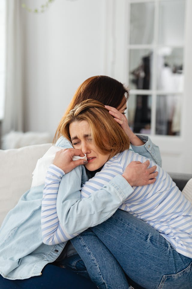 Two women hugging, one crying while the other comforts her