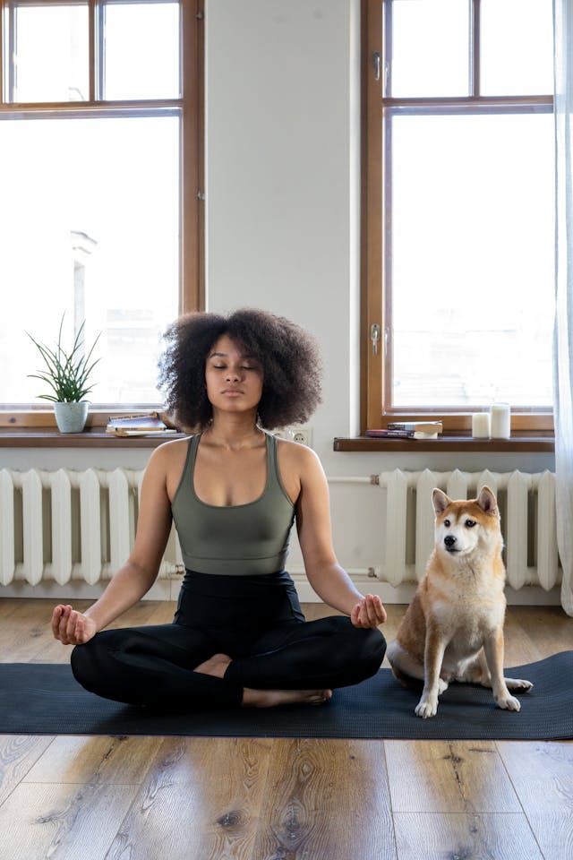 Woman practicing gentle yoga at home with her dog nearby