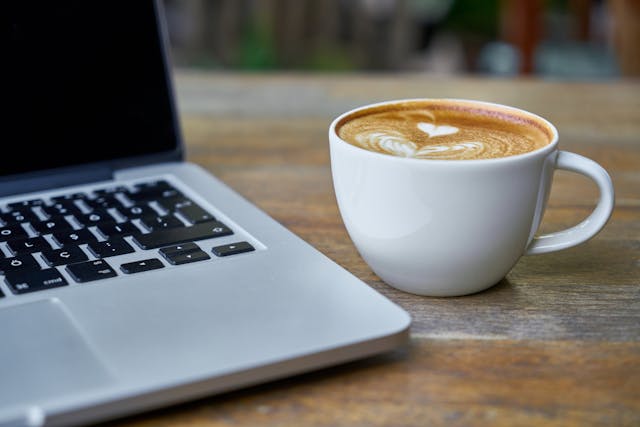 Laptop and coffee cup representing online donations ad subscriptions through Buy Me a Coffee